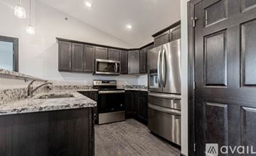 Rapid City apartment for rent - A kitchen with dark wood cabinets and stainless steel appliances.