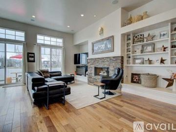 Midway house for rent - A living room with a black leather sofa and a stone fireplace.