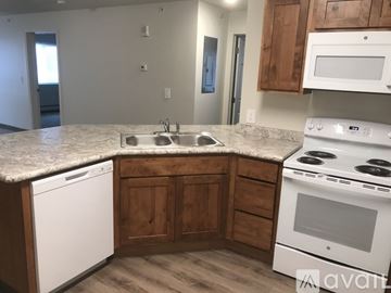 Great Falls apartment for rent - A kitchen with a white dishwasher and white oven with wooden cabinets.