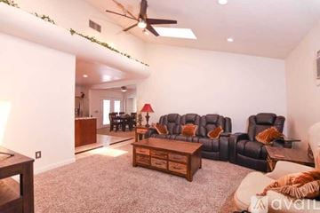 Santa Clarita house for rent - A living room with a grey carpet and a black leather sofa.