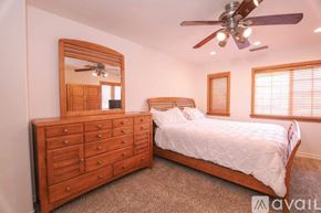 Santa Clarita house for rent - A bedroom with a large bed, a dresser with a mirror, and a ceiling fan.