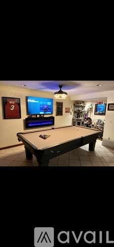 Miami house for rent - A room with a pool table and a TV mounted on the wall.