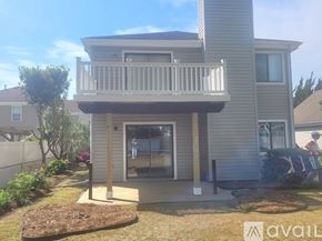 Virginia Beach condo for rent - A house with a balcony and a small garden in front.