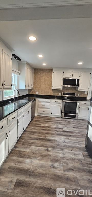 Williamsburg house for rent - A kitchen with white cabinets and a wooden floor.