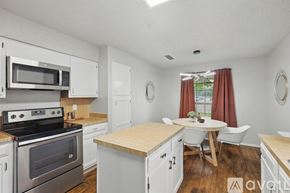 Garland house for rent - A kitchen with white cabinets and a wooden island.