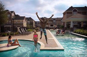 Denton apartment for rent - a man jumping into a swimming pool with people in a pool