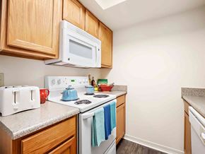 Metairie apartment for rent - a kitchen with a white stove and microwave and wooden cabinets