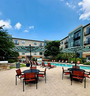 Round Rock apartment for rent - A poolside area with chairs and umbrellas.