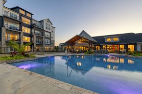 Belton apartment for rent - A large swimming pool in front of a building with a lit up fountain.