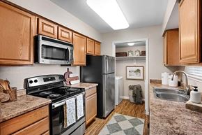 Littleton apartment for rent - A kitchen with wooden cabinets and a black stove top oven.