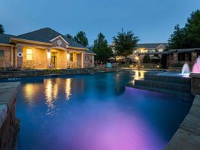 Plano apartment for rent - a large pool in front of a house at night