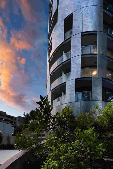Vancouver apartment for rent - A tall building with balconies and windows is surrounded by greenery.