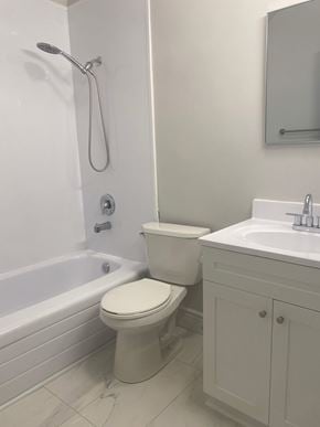 Bedford apartment for rent - A white toilet sits next to a white sink in a bathroom.
