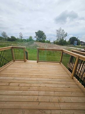 Corunna house for rent - A wooden deck with a black railing overlooks a grassy area.