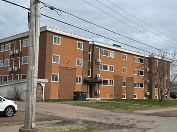 Amherst apartment for rent - A large brick apartment building with a white car parked in front.