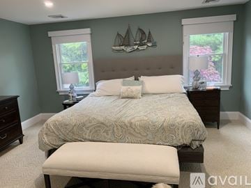 Mashpee house for rent - A bedroom with a large bed and a window with a view of a garden.