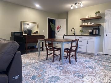 Demorest apartment for rent - A living room with a brown leather couch and a white dining table.