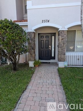 Miramar townhouse for rent - A house numbered 2574 with a black door and a tree in front.