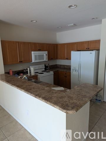 Miramar townhouse for rent - A kitchen with brown cabinets and a white fridge.