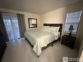Rotonda West apartment for rent - A bedroom with a large bed, a nightstand with a lamp, and a window with curtains.