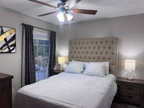 Irving house for rent - A bedroom with a large bed, a ceiling fan, and two lamps.