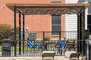 Irving house for rent - A patio with a pergola and chairs is in front of a brick building.