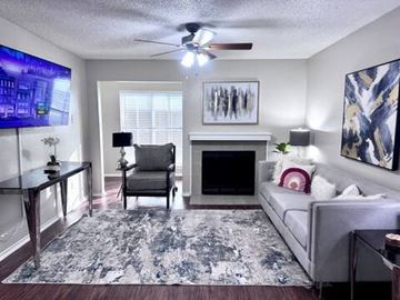 Irving house for rent - A living room with a grey couch, a black chair, a fireplace, and a painting on the wall.