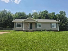 Oak Grove house for rent - A house with a grey roof and white windows is surrounded by a grassy field.