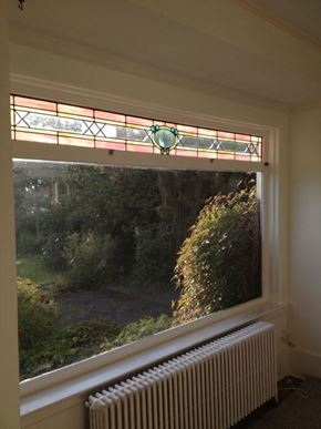 Victoria apartment for rent - A window with a stained glass design at the top and a white radiator below it.