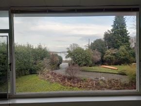 Victoria apartment for rent - A view from a window looking out to a rural landscape with a river and trees.