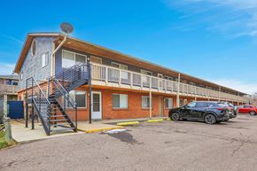 Lakewood apartment for rent - A black car is parked in front of a two-story apartment building with a balcony and stairs.