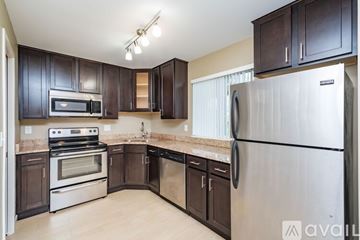 Coralville apartment for rent - A kitchen with dark brown cabinets and stainless steel appliances.