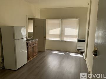 Los Angeles apartment for rent - A kitchen with a refrigerator, wooden cabinets, and a window with blinds.
