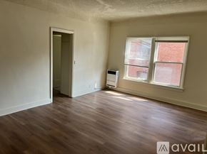 Los Angeles apartment for rent - A room with wooden floors and a window with a view of a brick building outside.