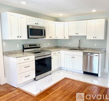 Newport apartment for rent - A kitchen with white cabinets and a wooden floor.