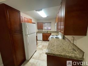 Miami apartment for rent - A kitchen with a granite countertop and wooden cabinets.