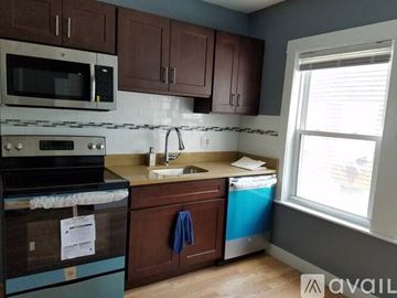 Boston apartment for rent - A kitchen with brown cabinets and a blue dishwasher.