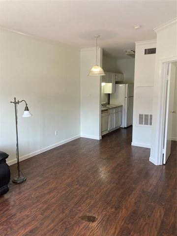 Austin apartment for rent - A room with wooden floors and a kitchen in the background.