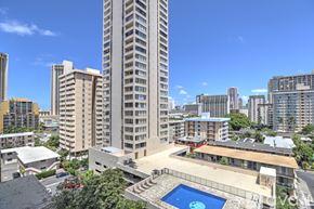 Honolulu apartment for rent - A tall building with a pool in the middle of a courtyard.