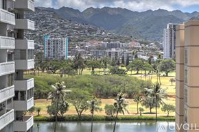 Honolulu apartment for rent - A view of a cityscape with buildings, trees, and mountains in the background.