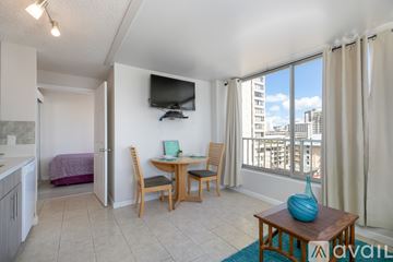 Honolulu apartment for rent - A living room with a television, a dining table with chairs, and a view of the city.