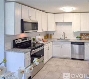 Jacksonville house for rent - A kitchen with white cabinets and appliances, a sink, and a stove.