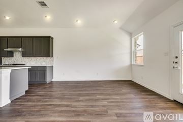 Heath house for rent - A spacious room with wooden flooring and a kitchen area with a stove top oven.