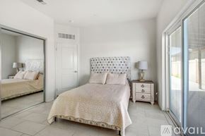 Indio house for rent - A bedroom with a large bed and a mirror on the wall.