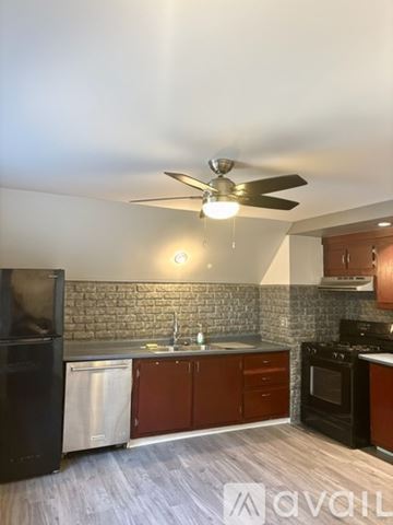 Rochester apartment for rent - A kitchen with a black refrigerator, a black stove, and a ceiling fan with lights.