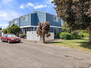 Kennewick apartment for rent - A red car is parked on the street in front of a blue building.