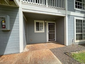 Kapolei apartment for rent - A grey house with a white door and a window with bars.