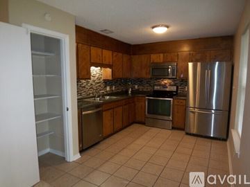Pensacola house for rent - A kitchen with a refrigerator, sink, and microwave.