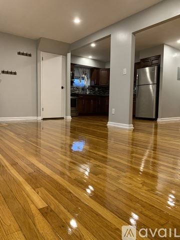 Queens apartment for rent - A kitchen with a refrigerator and wooden floors.