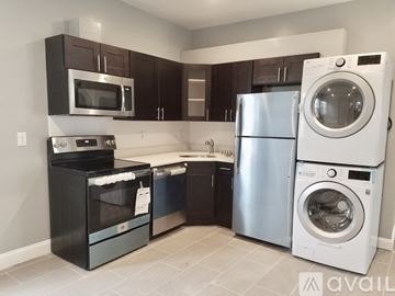 Boston apartment for rent - A kitchen with a black oven and microwave, a white refrigerator, and a white washing machine.